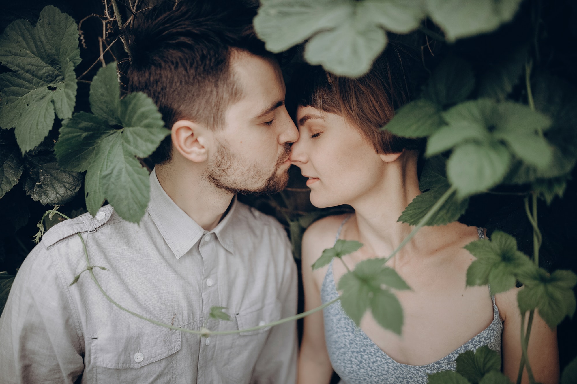 stylish hipster couple kissing in green leaves holding hands.jpg